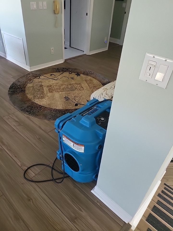 Dehumidifier running in living room with contents staged during water damage restoration